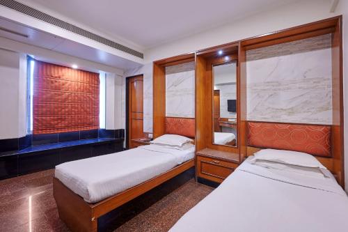 a small bedroom with two beds and a mirror at Hotel Karl Residency in Mumbai