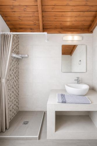a white bathroom with a sink and a mirror at Cavo Prima Kiotari in Gennadi
