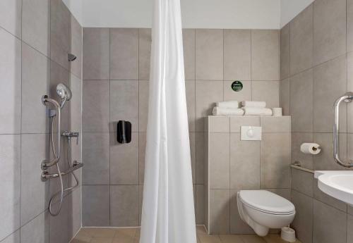 a bathroom with a shower with a toilet and a sink at B&B HOTEL Reims Tinqueux in Reims