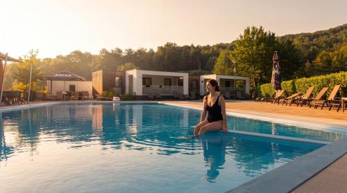 a woman sitting on the edge of a swimming pool at Mobile Homes Camping Plitvice in Smoljanac