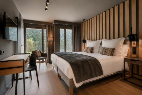a bedroom with a large bed with a desk and a desk at Hotel Naudi Boutique Adults only in Soldeu