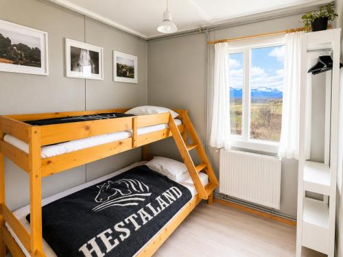 a bedroom with a bunk bed and a window at Hestaland Riverside Cottage in Staðarhús
