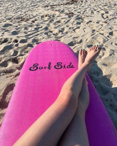 a woman laying on a pink surfboard on the beach at Yangyang Kai Guesthouse Surf in Yangyang
