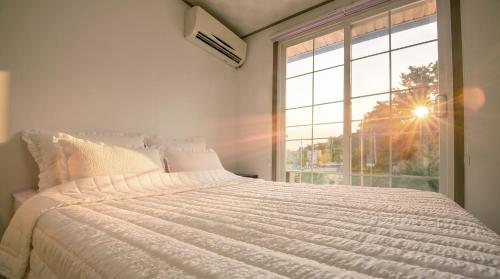 a bedroom with a white bed with a large window at Samcheok Healingcamp Pension in Samcheok