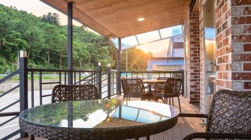 a patio with a glass table and chairs on a deck at Samcheok Healingcamp Pension in Samcheok