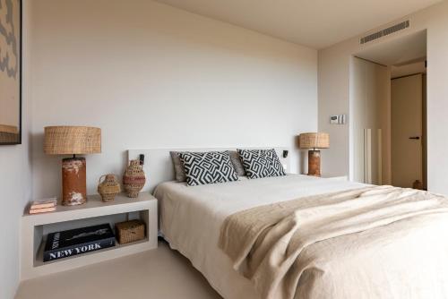 a white bedroom with a bed and two lamps at Villa Gara exclusive luxury villa with heated pool in Lajares