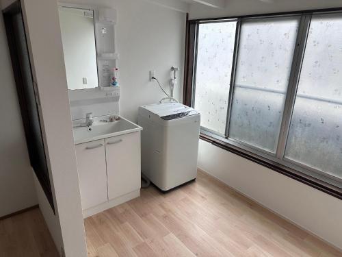 a bathroom with a sink and a washer and dryer at 勝浦の家 in Katsuura