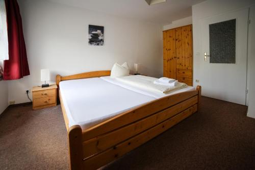 a bedroom with a wooden bed with white sheets at Ferienhotel Zwotatal in Klingenthal
