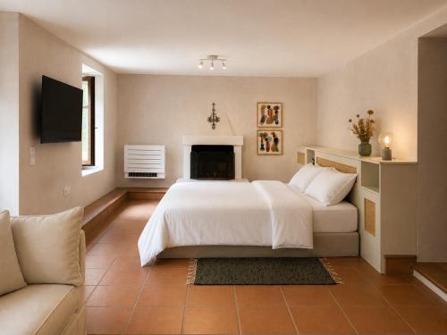 a bedroom with a white bed and a fireplace at The Cottage in the Trees in Tsagarada