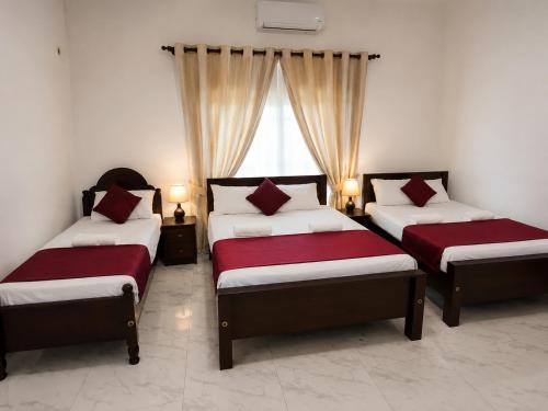 three beds in a room with a window at Glory Rajarata Lakeside Resort in Anuradhapura