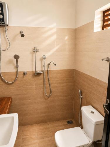 a bathroom with a shower and a toilet and a sink at Glory Rajarata Lakeside Resort in Anuradhapura