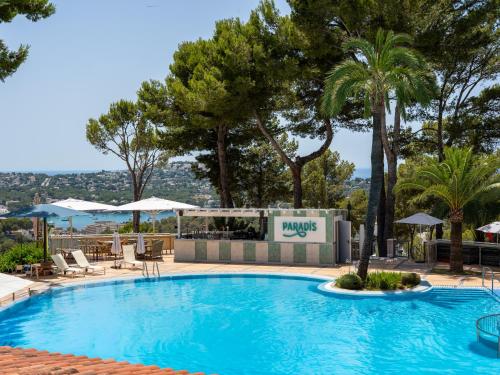 a swimming pool with palm trees and a hotel at Hilton Mallorca Galatzo in Paguera