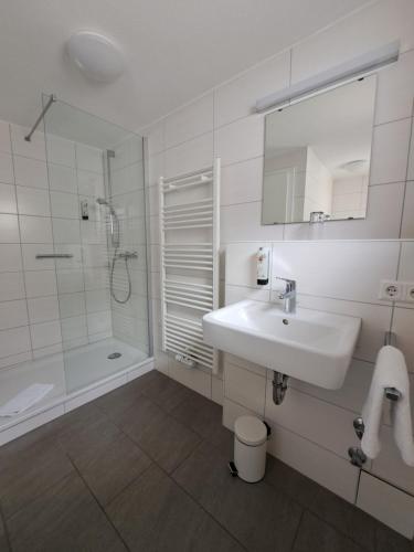 a white bathroom with a sink and a shower at Hotel zur Post in Weilheim an der Teck