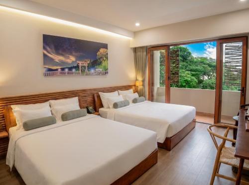 two beds in a room with a window at Memories Hotel in Bảo Lộc