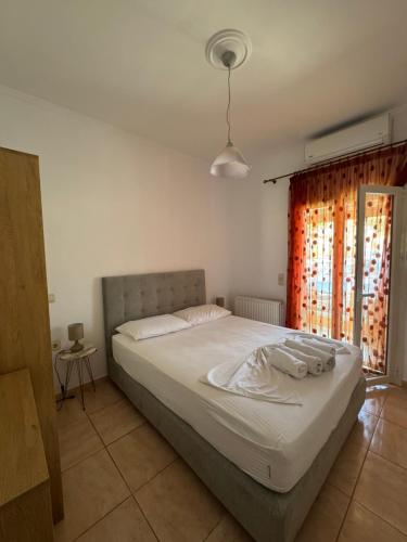 a bedroom with a large white bed and a window at Eleana's apartments in Gouvia