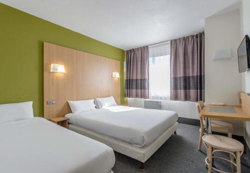 a hotel room with two beds and a desk at B&B HOTEL Nîmes Ville Active 3 étoiles in Nîmes