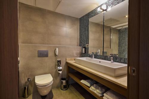 a bathroom with a sink and a toilet and a mirror at Avantgarde Urban Levent in Istanbul