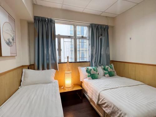 two beds in a room with a window at 利園賓館 in Hong Kong