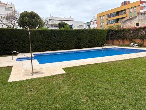 a swimming pool in a yard next to a hedge at MalagaSuite Dreamy Village in Arroyo de la Miel