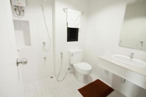 a white bathroom with a toilet and a sink at The Viewpoint Hotel in Ban Wat Tha Maprang