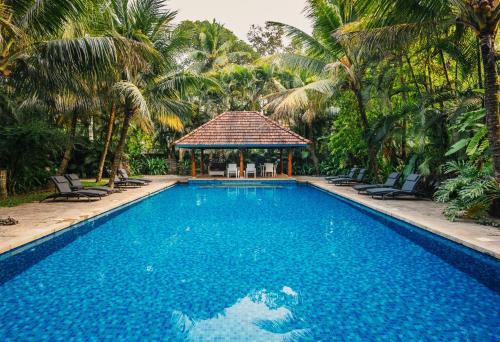 a swimming pool with a gazebo and palm trees at Indian Summer House in Mūvattupula