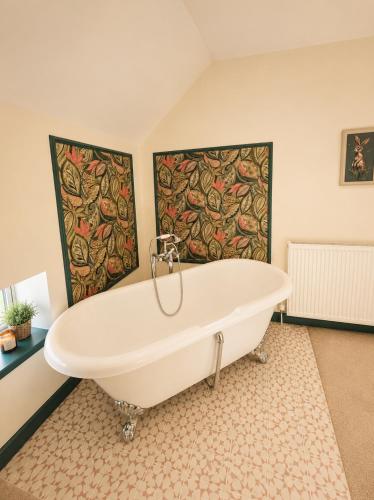 a bath tub in a bathroom with paintings on the wall at Farrier's Rest in Belford