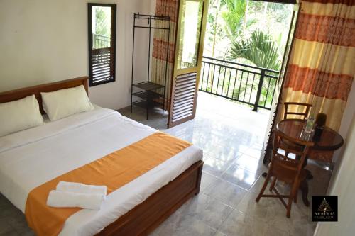 a bedroom with a bed and a table and a balcony at Aurelia Grand Hotel in Kitulgala