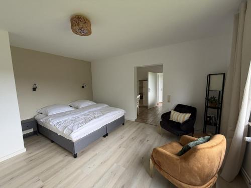 a bedroom with a bed and two chairs in a room at Gemütliche Ferienwohnung direkt am Waldrand in Dörentrup