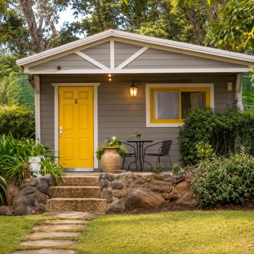 a small house with a yellow door and a table at שורשי הגליל - 6 בקתות מדהימות עם ג'קוזי, גינה וקרבה לנחלים in Yuval