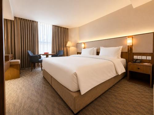 a hotel room with a large bed and a desk at La Casa Hotel Amman by FHM in Amman