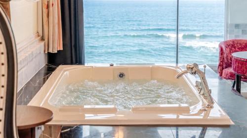 a bath tub with a view of the ocean at Youngduk Sea & Spa Pension in Yŏngdŏk