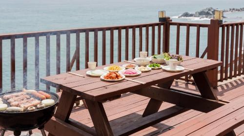 a wooden table with plates of food on a balcony at Youngduk Sea & Spa Pension in Yŏngdŏk