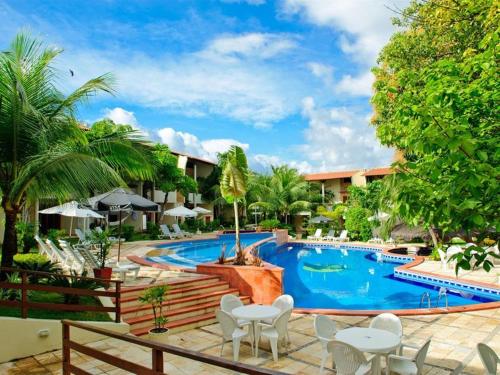 a pool at a resort with white tables and chairs at Chalet Solar Pipa in Pipa