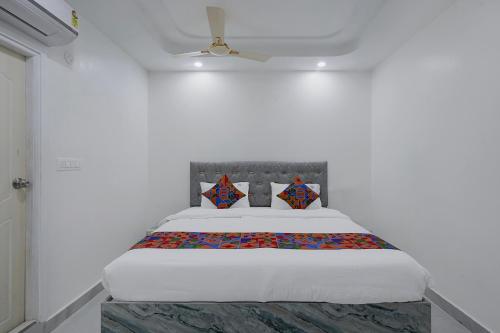 a bed in a white room with a white bedspread at FabHotel Blue Birds in Bangalore