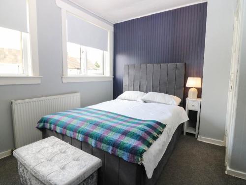 a bedroom with a large bed with a plaid blanket at 6 Niddrie Marischal Road in Edinburgh