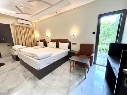 a bedroom with two beds and a chair and a window at Hotel Fivetel in kolkata