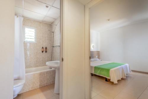 a bathroom with a bed and a tub and a sink at Cabot Club Torreblanca in Sa Coma