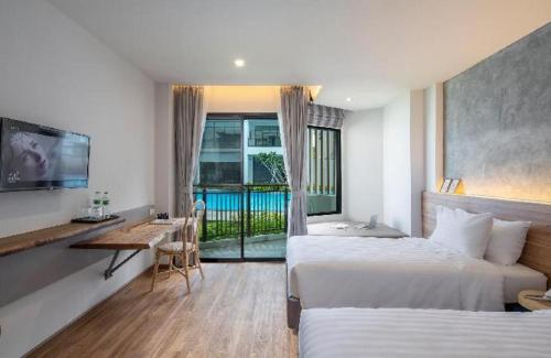 a hotel room with two beds and a table and a desk at i Tara Private in Ban Laem Phak Bia (1)