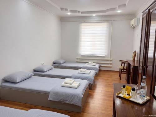 a room with four beds and a table and a window at Хостел18А in Nukus