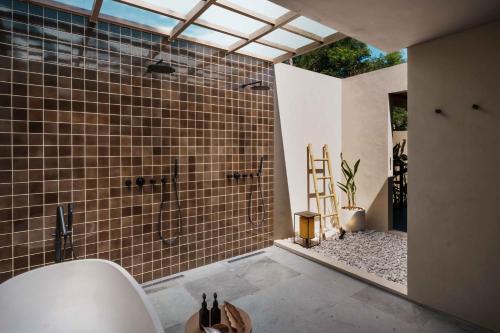 ein Badezimmer mit Dusche und braunen Fliesen in der Unterkunft Hotel Lumi Gili Trawangan in Gili Trawangan