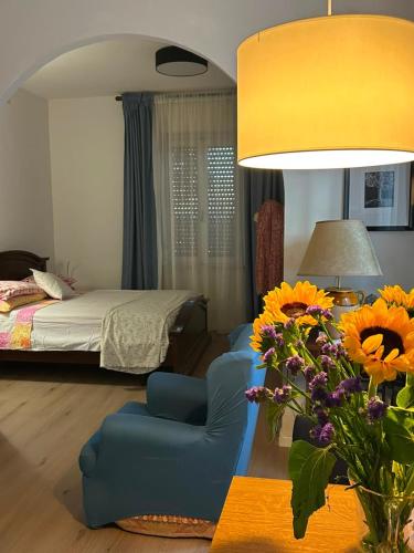 a living room with a bed and a blue chair and flowers at Appartamento con giardino e posto auto privato in Follonica