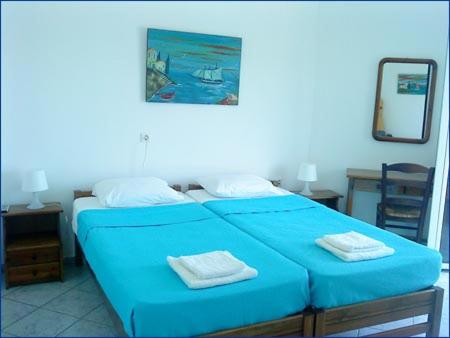 a bedroom with a blue bed with two towels on it at Haris Apartments in Armenistis