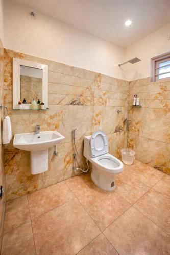 a bathroom with a toilet and a sink at Amara Lux Rivage wynad in Vythiri