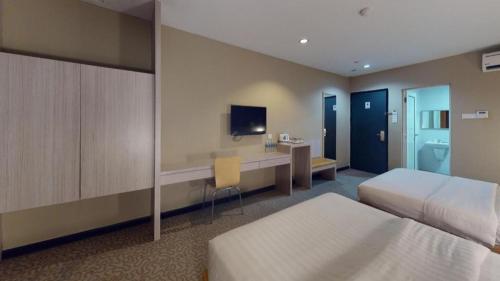 a hotel room with two beds and a desk at Clover Hotel in Johor Bahru
