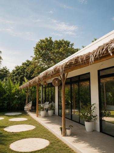 a patio with a thatched roof and plants at CASA BUKO Tropical Homes El Nido in El Nido