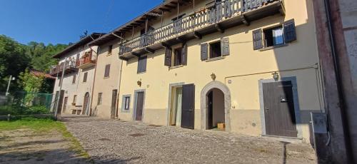 a large yellow building with a balcony on the side at Nespello Tourist Accommodation in Costa di Serina