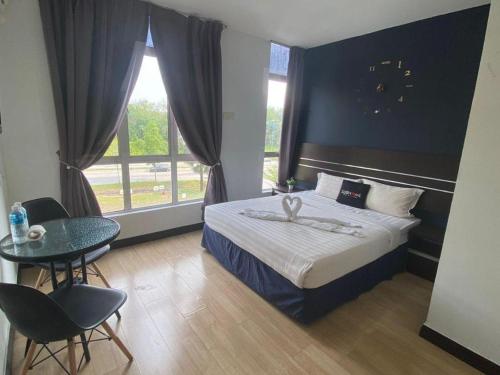 a bedroom with a bed and a table and a window at Alia Express Sendayan in Kampong Gadong Jaya