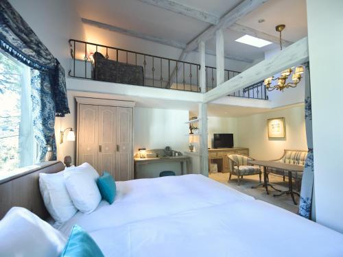 a bedroom with a white bed and a balcony at Auberge de Primavera in Karuizawa