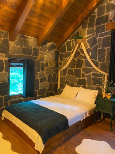 a bedroom with a bed in a stone wall at Lavinya Suit Bungalov in Rize