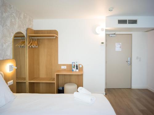 a hotel room with a bed and a desk at BRIT HOTEL CONFORT Roissy Saint-Witz in Saint-Witz